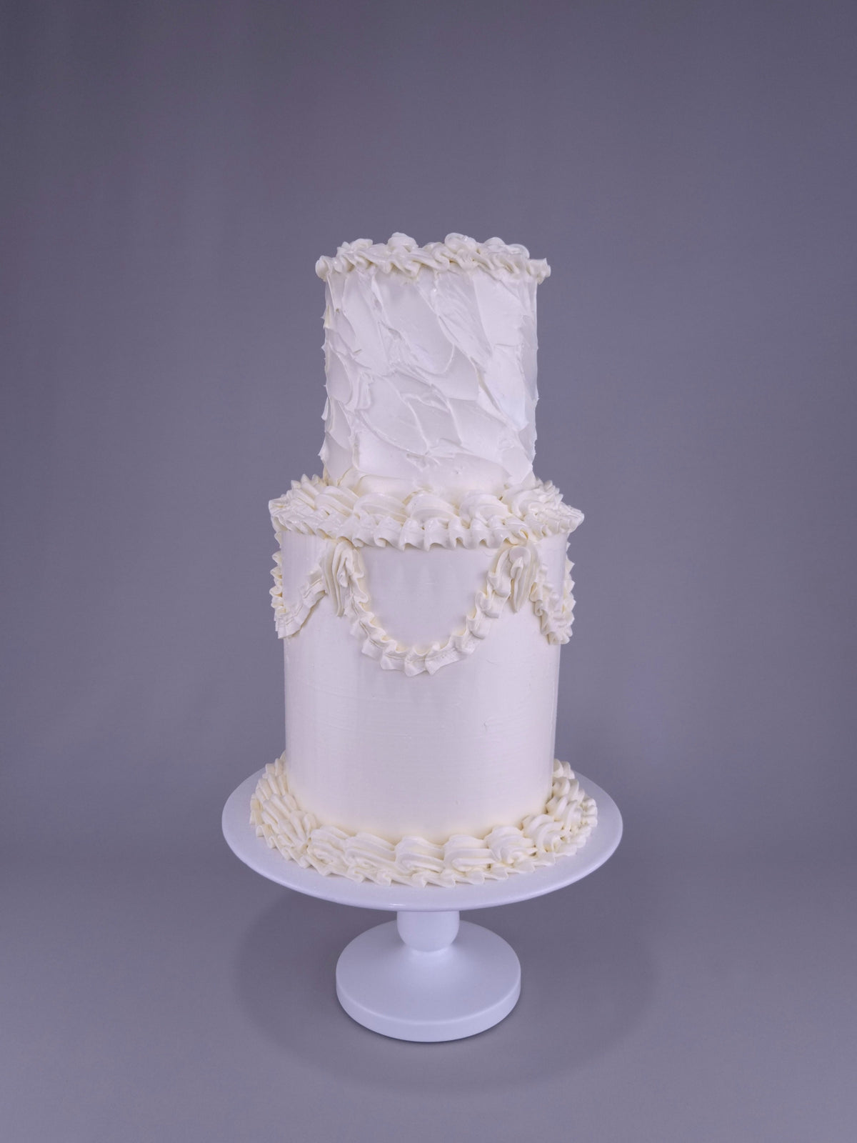 Zweistöckige weiße Hochzeitstorte mit filigranen Girlanden und strukturierter Oberfläche