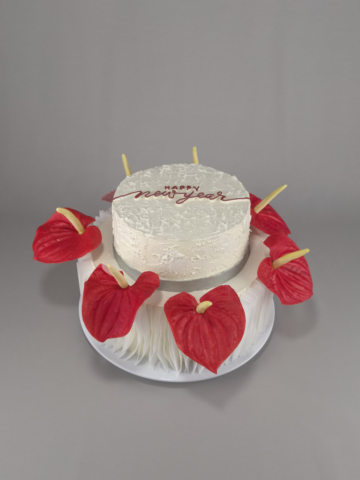 Zweistöckige weiße Torte mit roten Blüten und Neujahrsgruß