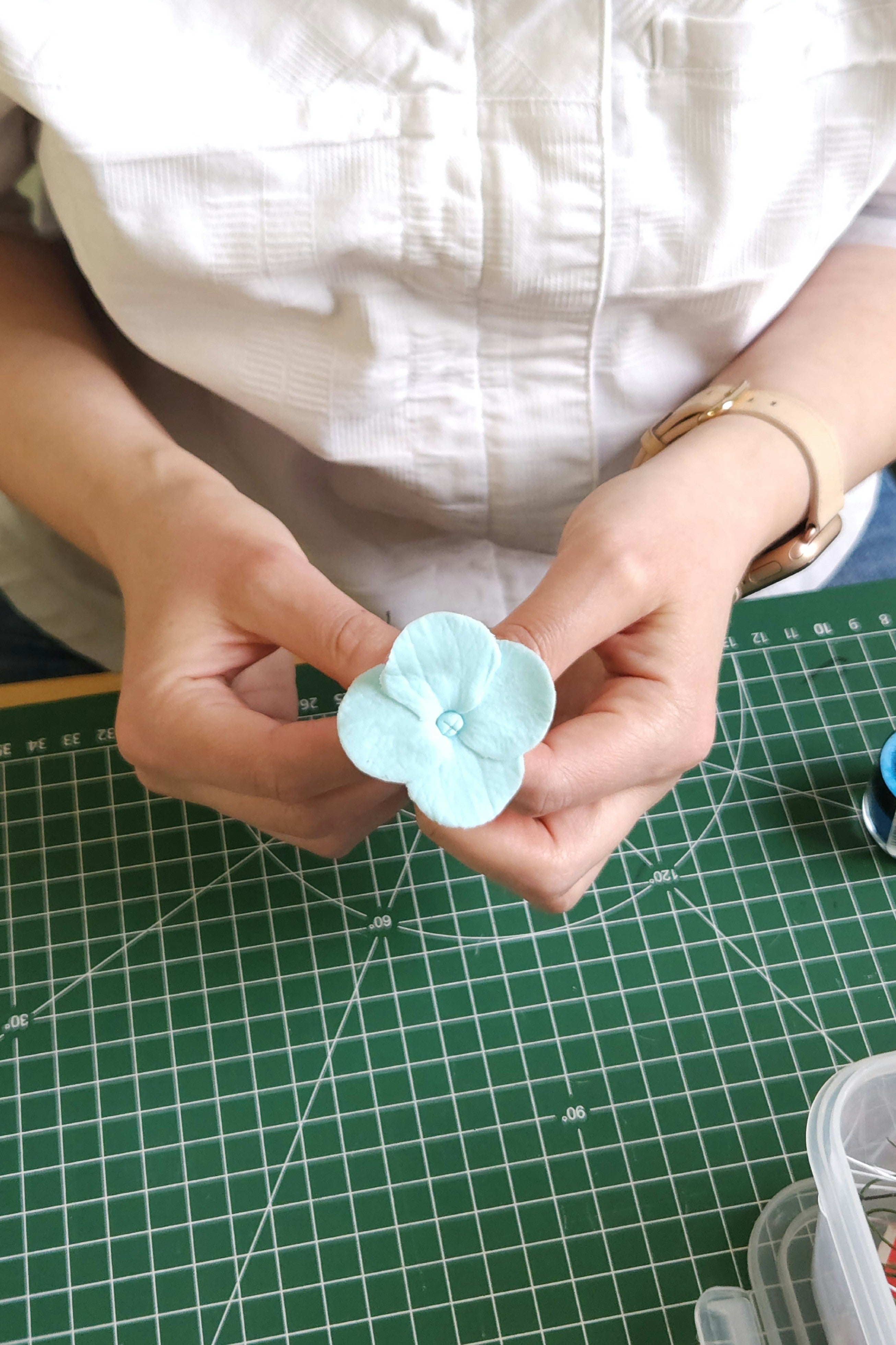 Konditormeisterin fertigt essbare Hortensienblume aus Zucker-Blütenpaste – liebevolle Handarbeit für exklusive Tortendekoration.