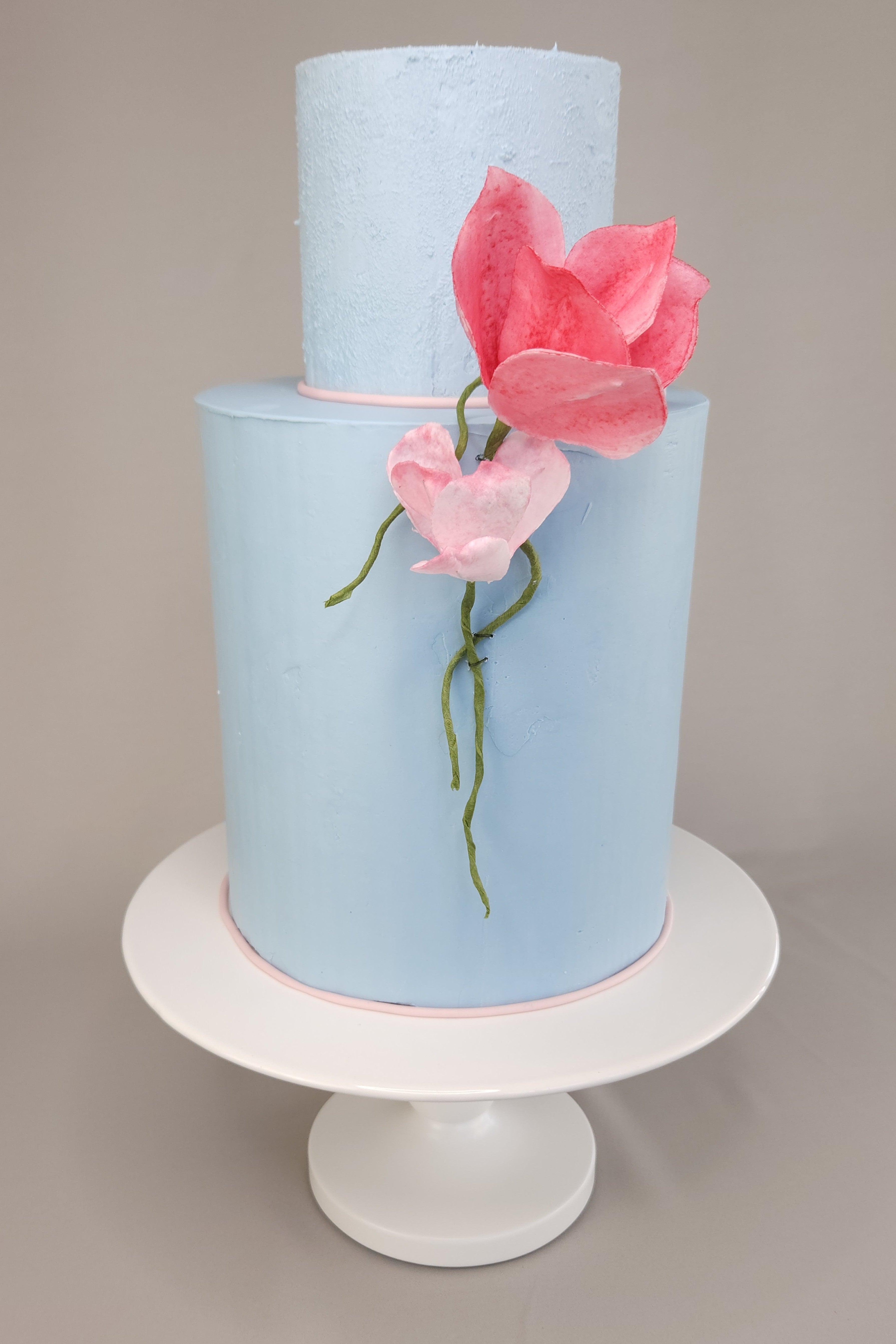Elegante 2-stöckige Torte mit blauer Ganache und essbaren Papierblumen – perfekt als Hochzeitstorte oder für besondere Anlässe.