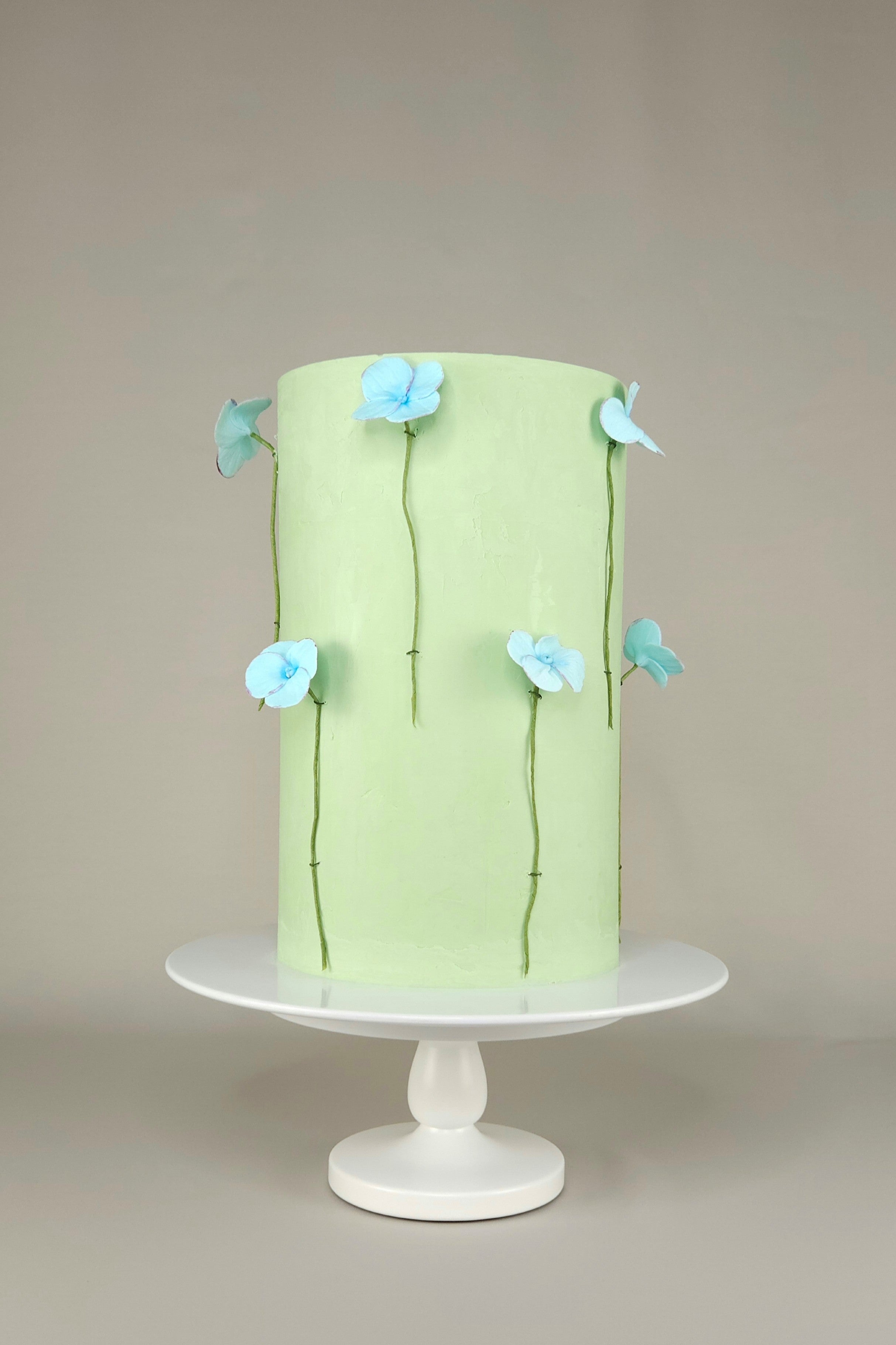 Einstöckige grüne Torte mit blauen Hortensienblüten aus Zucker-Blütenpaste – florale Design-Torte, handgemacht in Berlin.