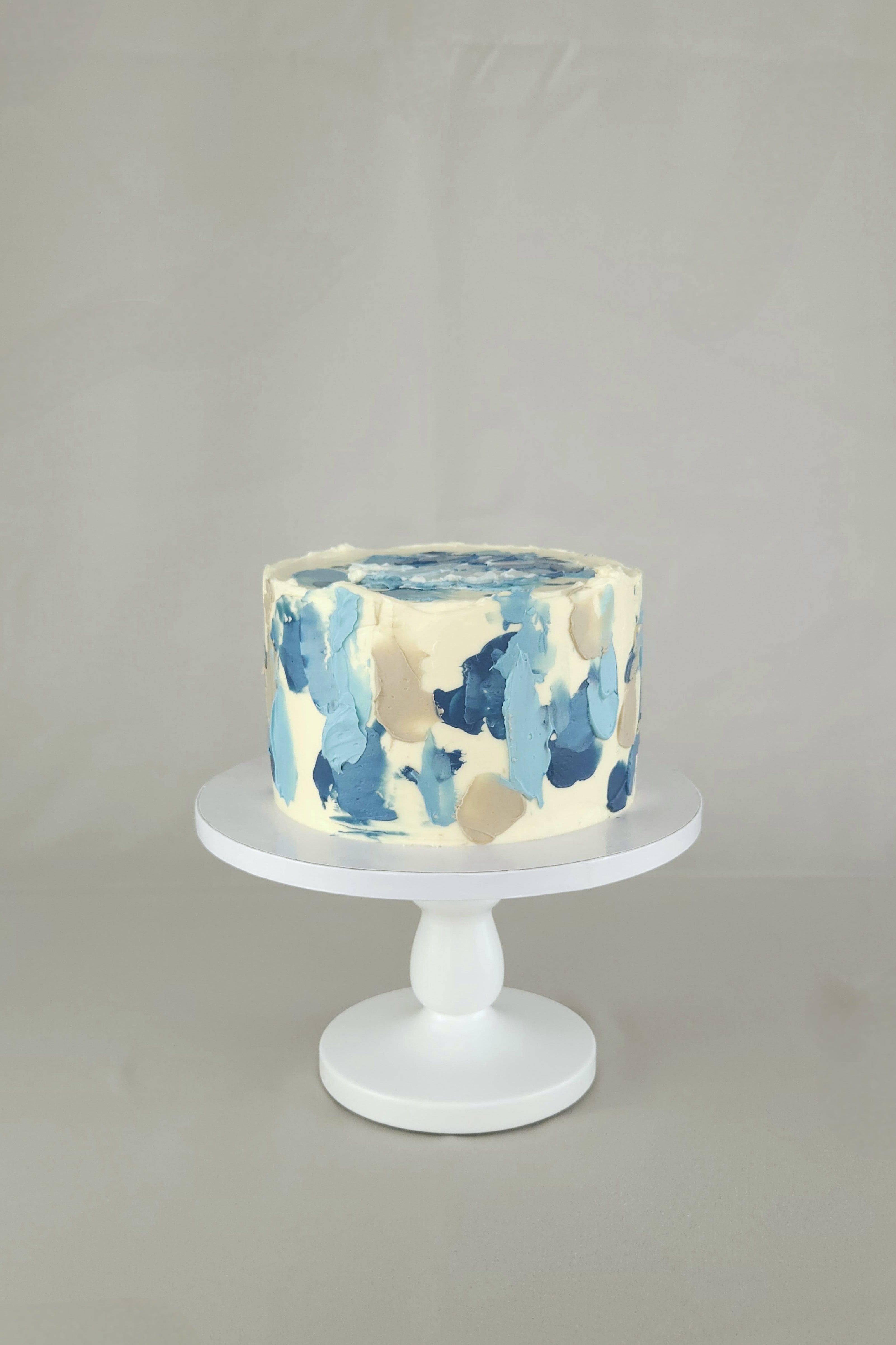 Einstöckige Torte mit blau-cremefarbenem Wellenmuster und heller Ganache – handgemacht in Berlin.