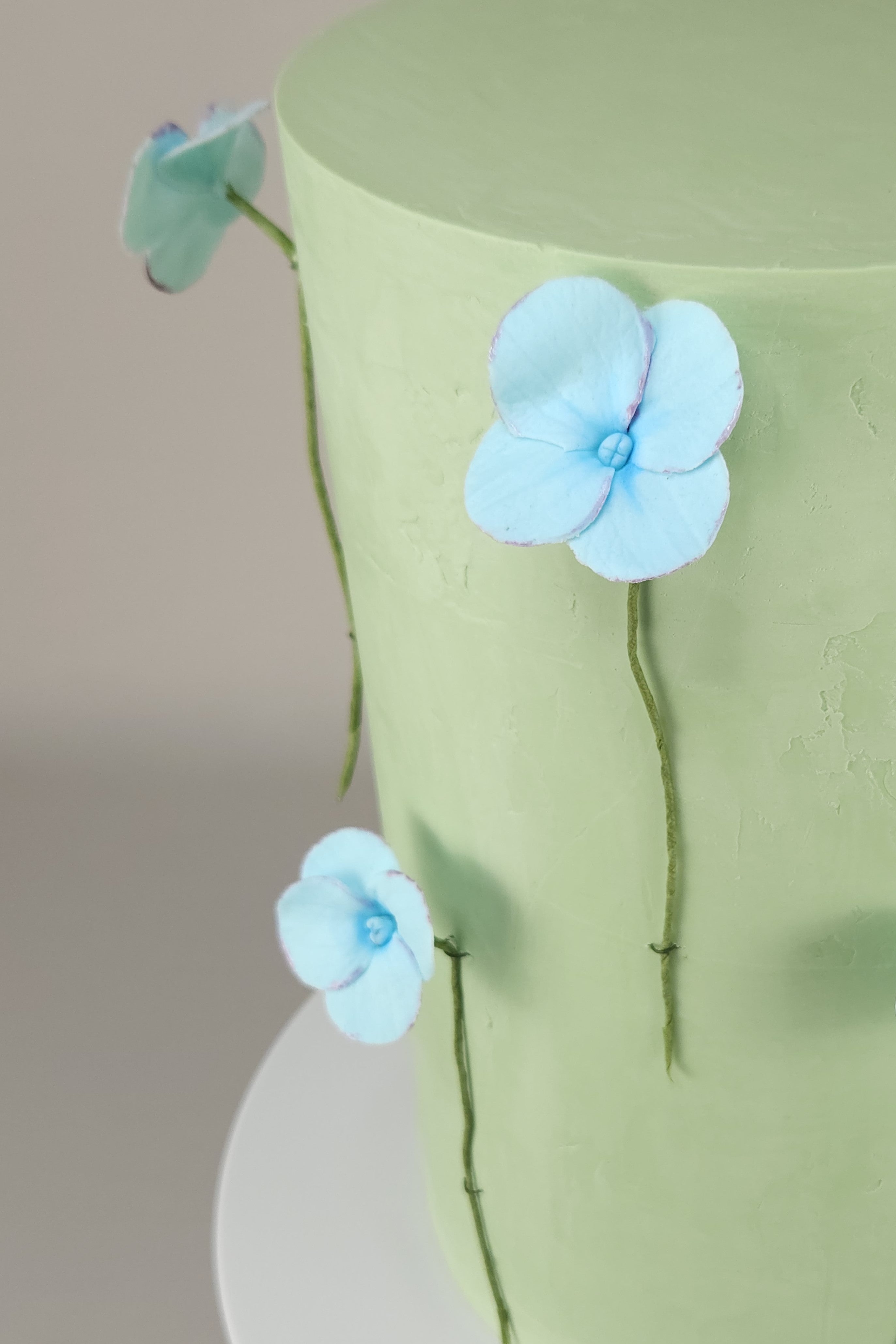 Detailansicht von handgefertigten Zucker-Hortensien auf grüner Ganache-Torte – perfekte Wahl für natürliche Festlichkeiten.
